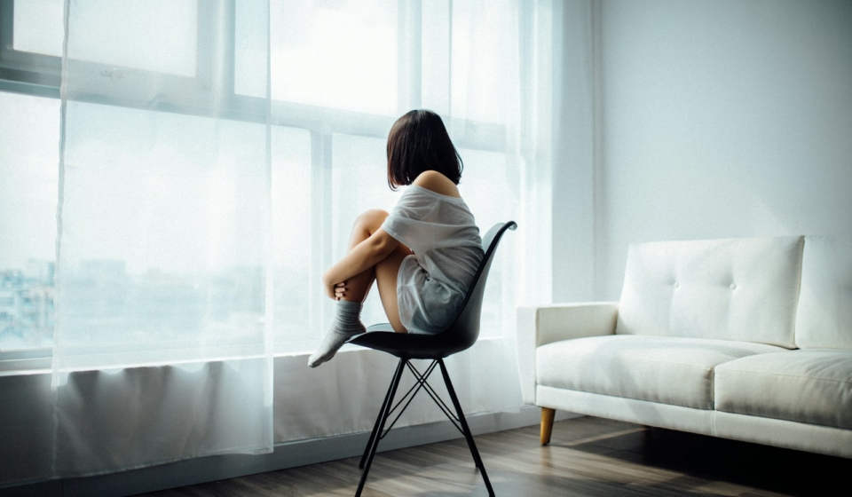 woman sitting on black chair in front of glass-panel window with white curtains